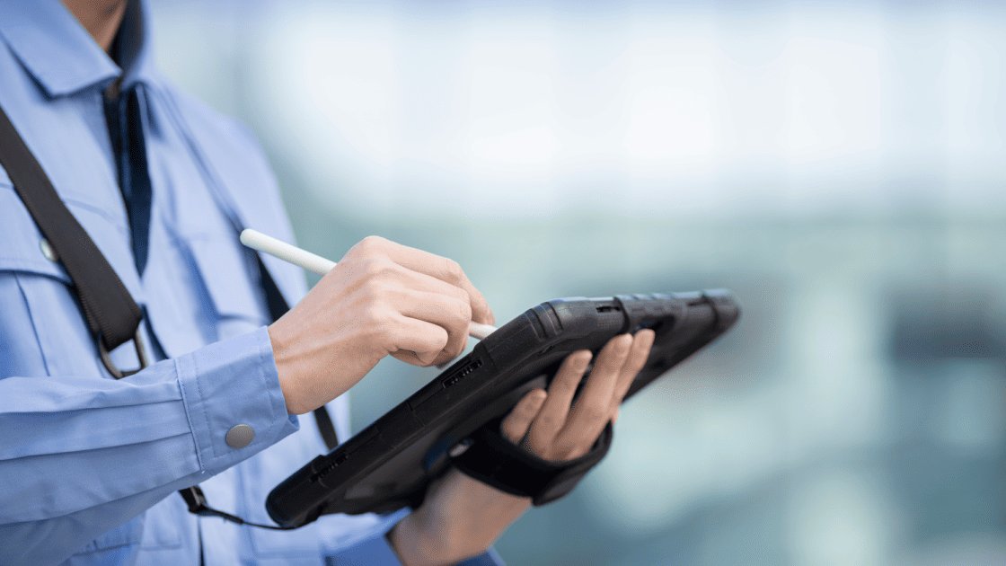 作業服を着たスタッフがスタイラスペンでタブレット端末に入力し、紙の冊子に代わるデジタル検索で業務を効率化している様子